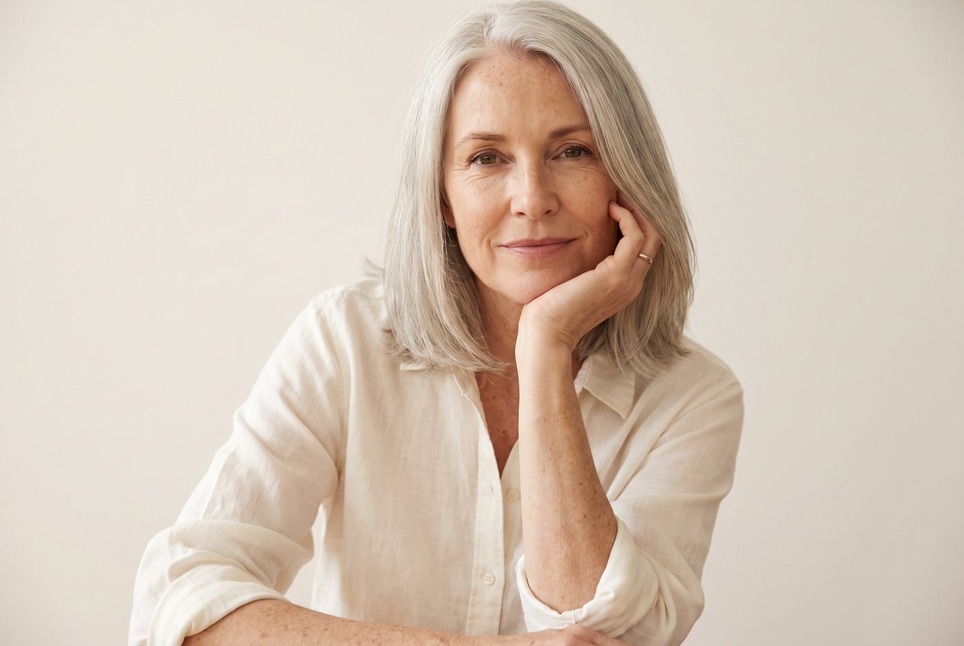 Woman in her fifties smiling, chin resting on her hand